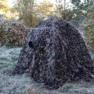 pixelpenguin- Een camouflagenettent midden in een veld.