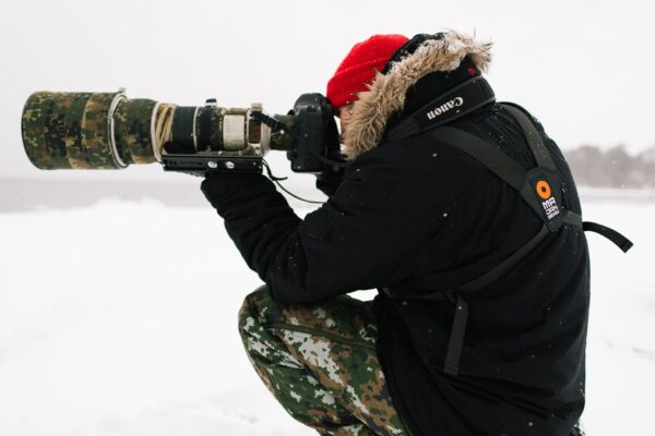 pixelpenguin- Een man met een lensdrager die het besneeuwde landschap vastlegt.